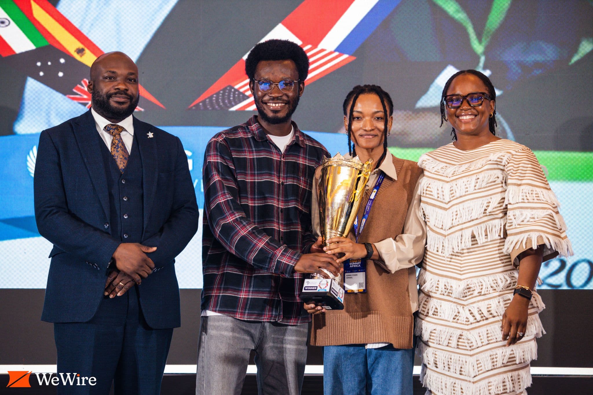 Four people stand together with a trophy at the Startup World Cup Accra regional event.