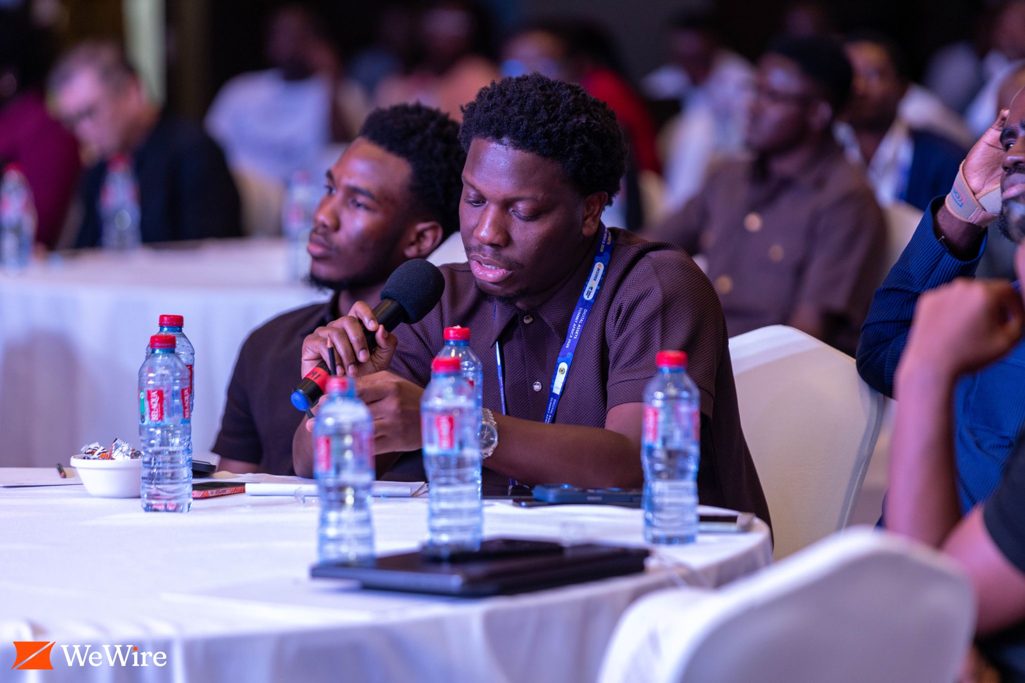 An attendee holds a microphone at a table during the event.